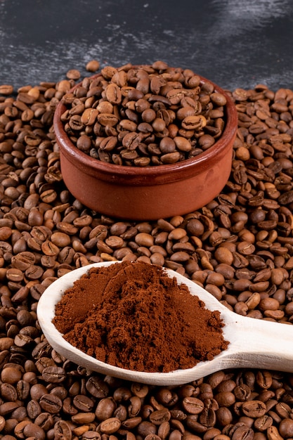 coffee beans with ground coffee in wooden spoon