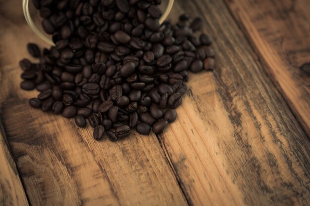 Coffee beans on a wooden table coming out of a bowl