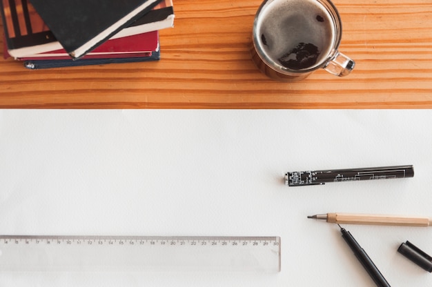 Coffee and books near drafting supplies