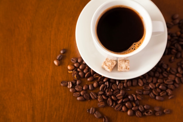 Coffee cup and beans on wooden table