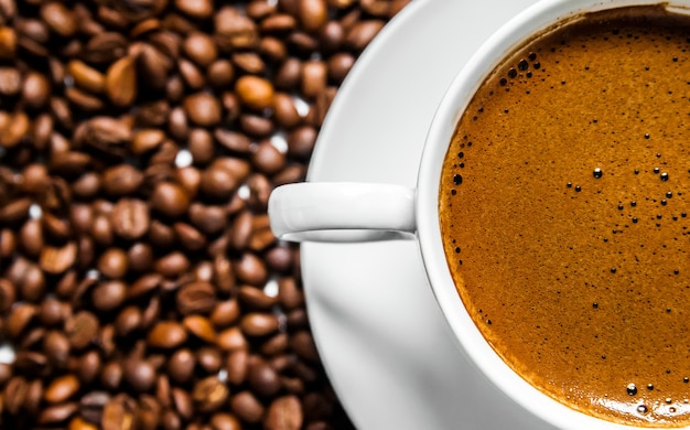 Free photo coffee cup and coffee beans on table, top view, love coffee, brown coffee beans isolated on white background, hot coffee cup with coffee beans