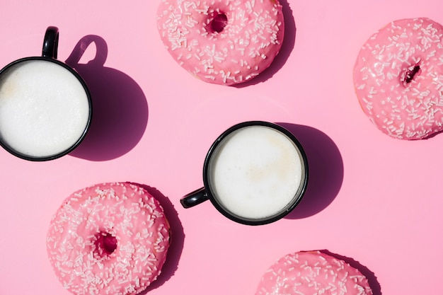 Free photo coffee cup and donuts on pink background