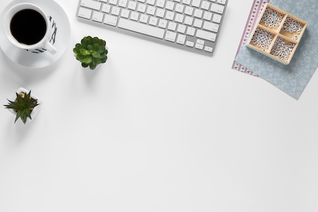 Free photo coffee cup; keyboard; cactus plant and box with card papers on workplace