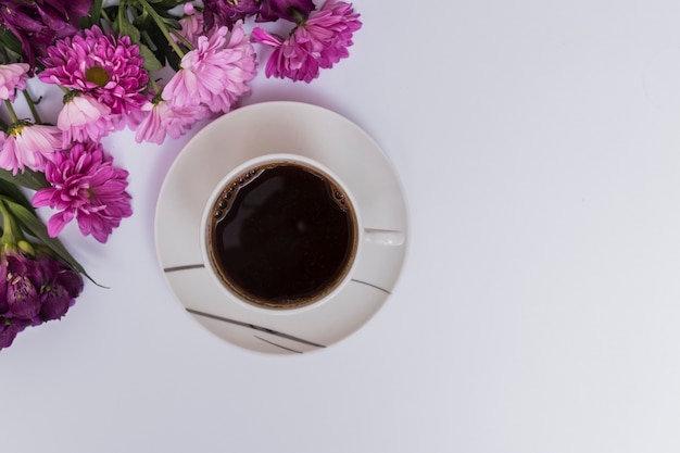 Free photo coffee cup and purple flowers