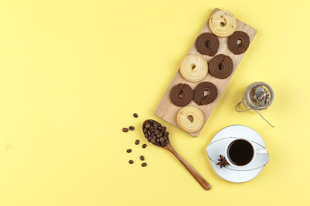 Free Photo coffee in cup with coffee beans, biscuits, dried herbs on yellow background