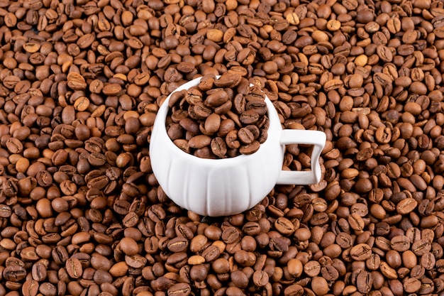 Free Photo coffee cup with coffee beans on coffee surface