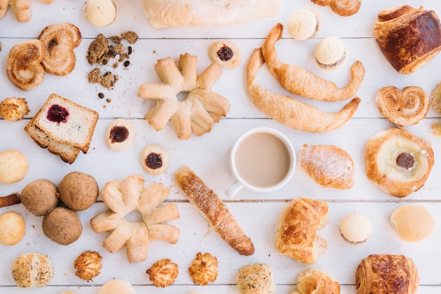 Coffee cup with different bakery on wooden table