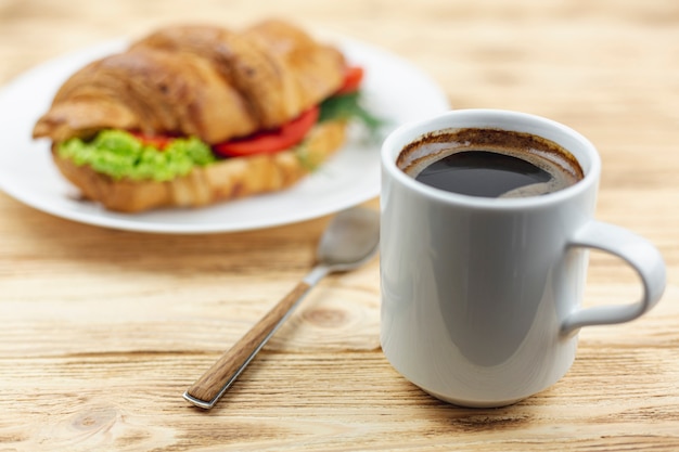 Coffee cup with a sandwich on a white plate