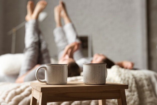 Coffee cups on the table with couple behind in bed