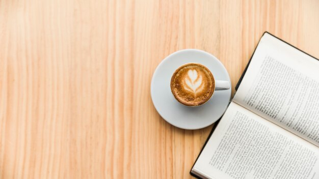 Coffee latte and open book on wooden surface