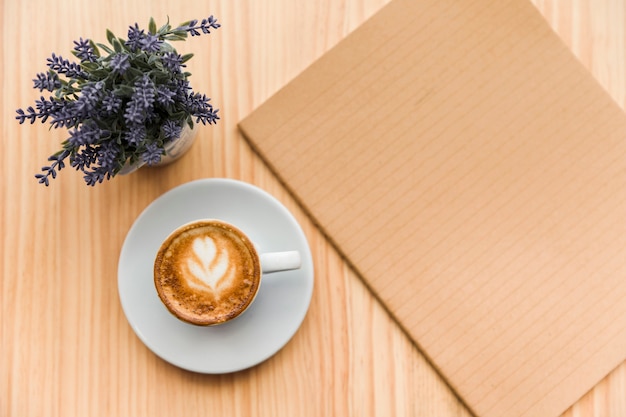 Coffee latte with lavender flower and notebook on wooden background