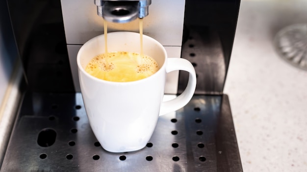 Free photo coffee machine pouring coffee with into a cup