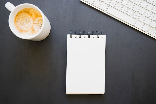 Coffee mug, notebook and keyboard