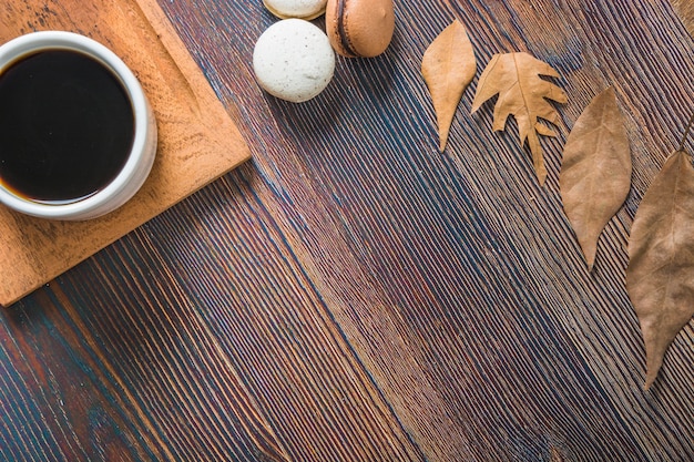 Coffee near leaves and macaroons