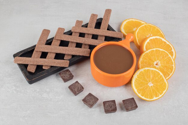 Coffee, orange slices, chocolate and biscuits on marble surface