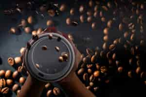 Free photo coffee paper cups with coffee beans on a dark background. pattern and creative background concept for cafes.