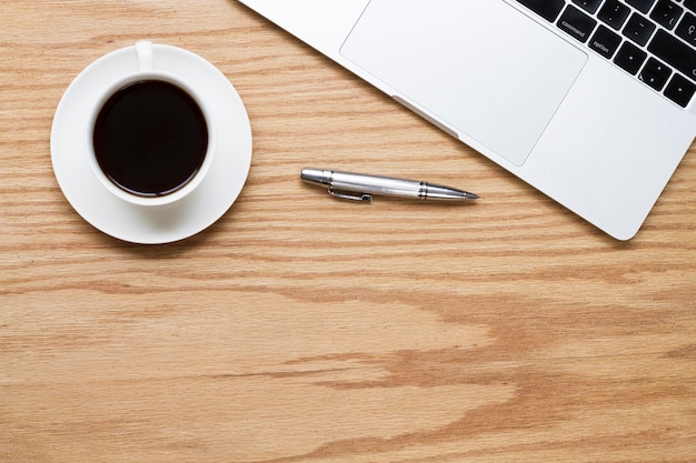 Coffee next to pen and laptop