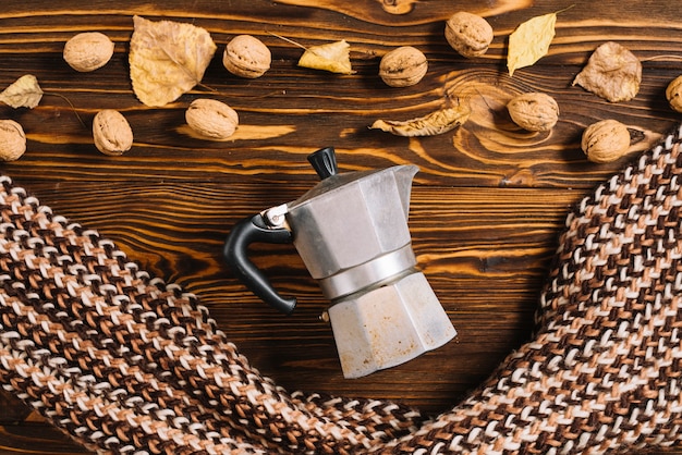 Coffee pot and scarf near walnuts and leaves