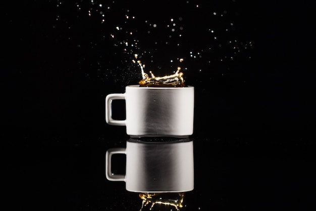 Free photo coffee splashes in white cup on black background