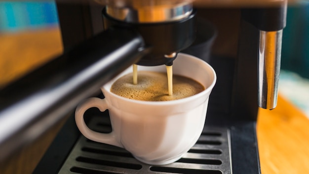 Coffee with frothing pouring from espresso machine