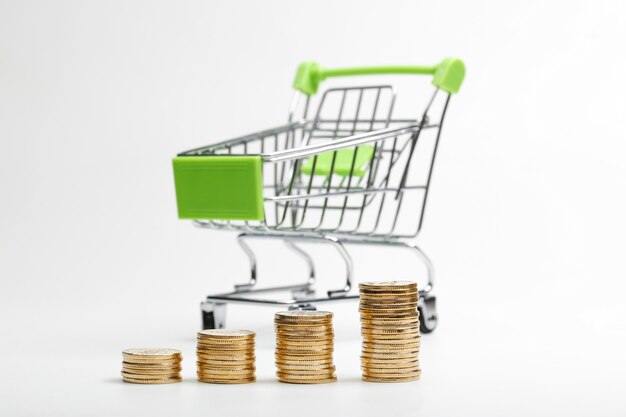 COINS pile and shopping cart on a white background