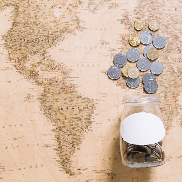 Free photo coins spilling from jar over the world map