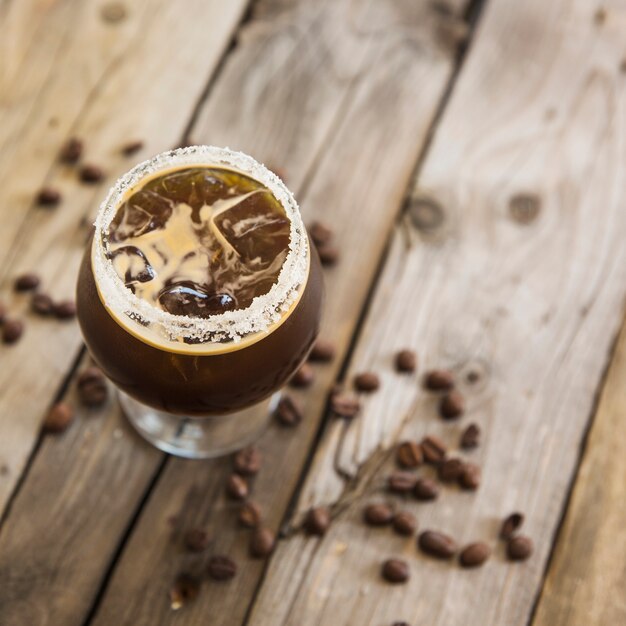 Cold coffee drink with ice on wooden background