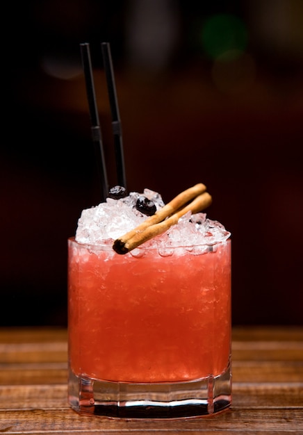 Cold red cocktail with cinnamon sticks