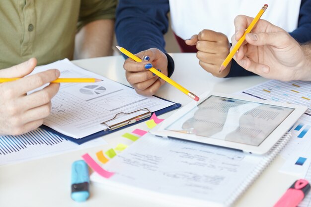 Collaborative work. Group of marketing experts working together on startup project, sitting at table with sheets of paper and digital tablet.