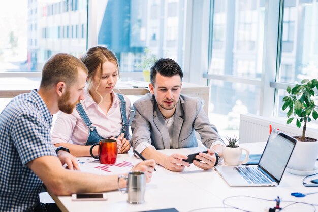 Colleagues browsing smartphone during discussion