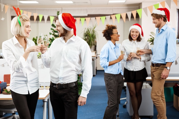 Free Photo colleagues celebrating christmas party in office drinking champagne smiling.