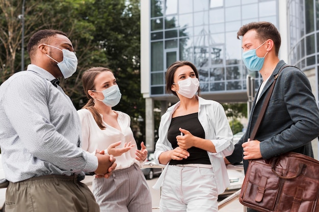 Colleagues chatting outdoors during pandemic with face masks