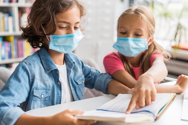 Free photo colleagues doing their homework while wearing a face mask