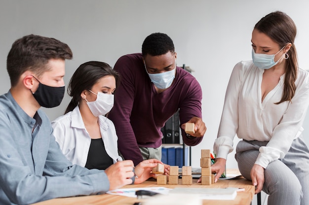 Colleagues having a meeting in the office during pandemic with medical masks on