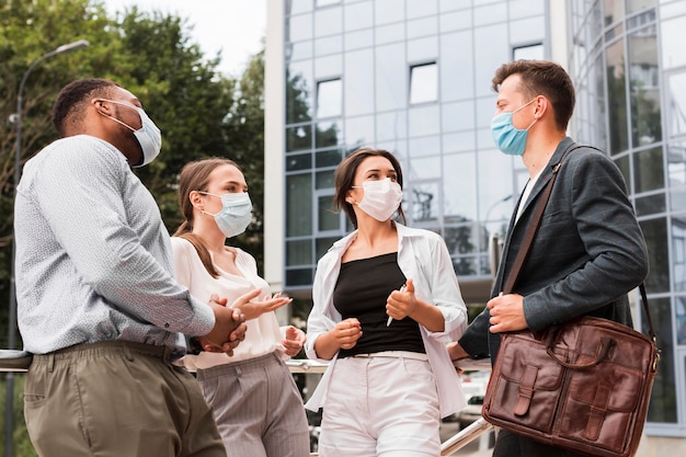 Colleagues outdoors during pandemic chatting with masks