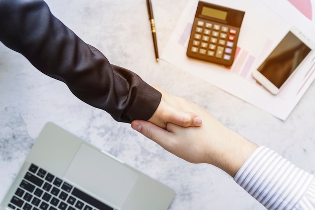 Colleagues shaking hands above desk