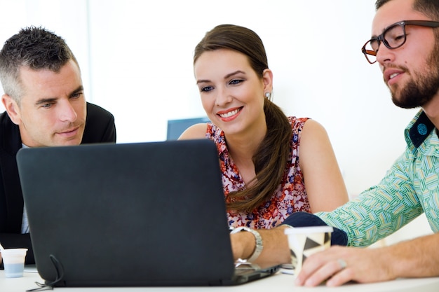 Colleagues sitting by table and using laptop