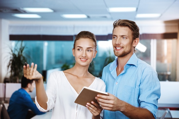 Free Photo colleagues smiling, speaking, holding notebook, over office