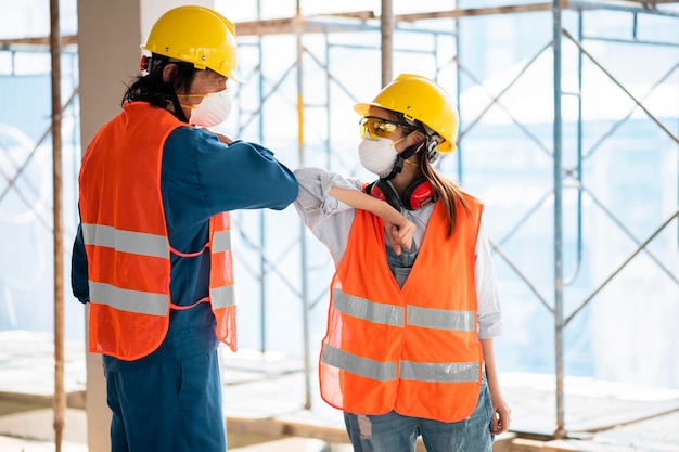 Colleagues with safety equipment touching elbow