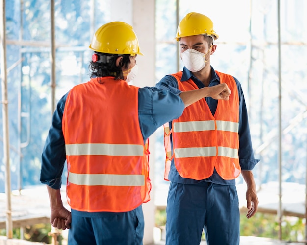 Colleagues with safety equipment working with blueprints