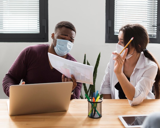 Colleagues at work in office during pandemic wearing medical masks