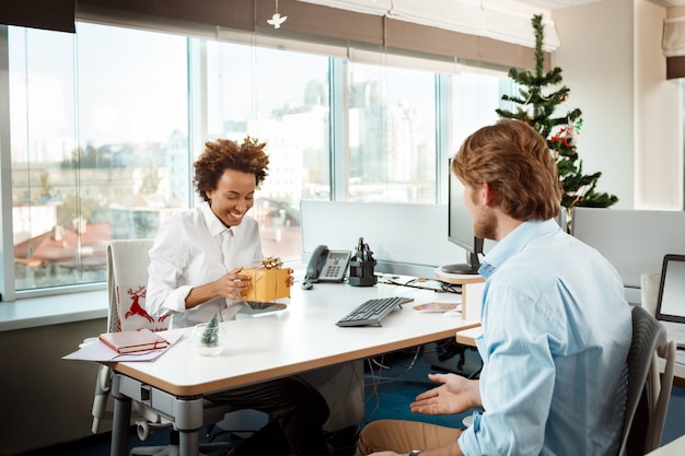 Colleagues working in office on christmas day giving presents.