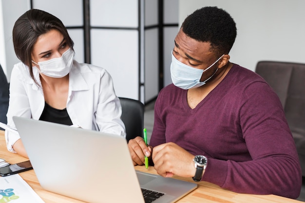 Colleagues working together during pandemic in the office with masks on