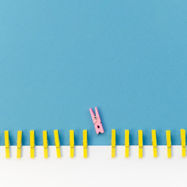 Collection of clothespins next to a pink one with copy space