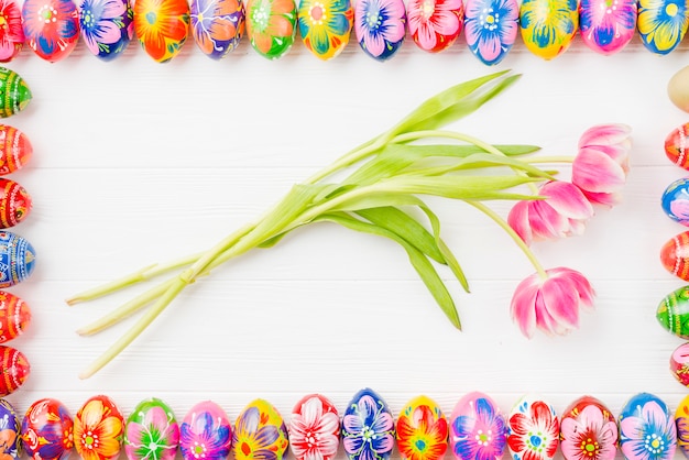 Collection of colored eggs on edges and flowers