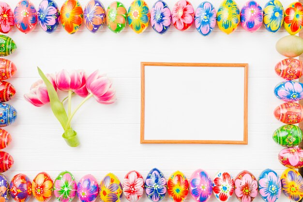 Collection of colored eggs on edges, frame and flowers