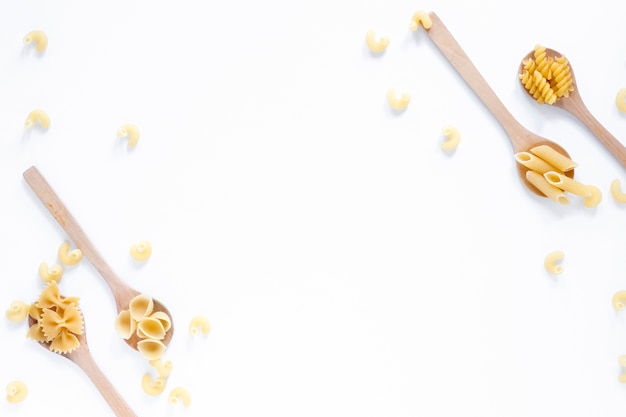 Free photo collection of spoons filled with various dry pasta over white backdrop