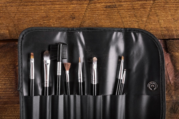 Collection of various makeup brushes on wooden background