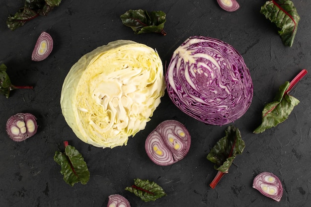 Colored cabbages fresh ripe and sliced yellow and purple cabbages and green leafs isolated on grey background