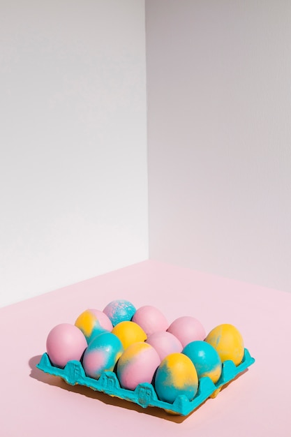 Free photo colored easter eggs in big rack on pink table